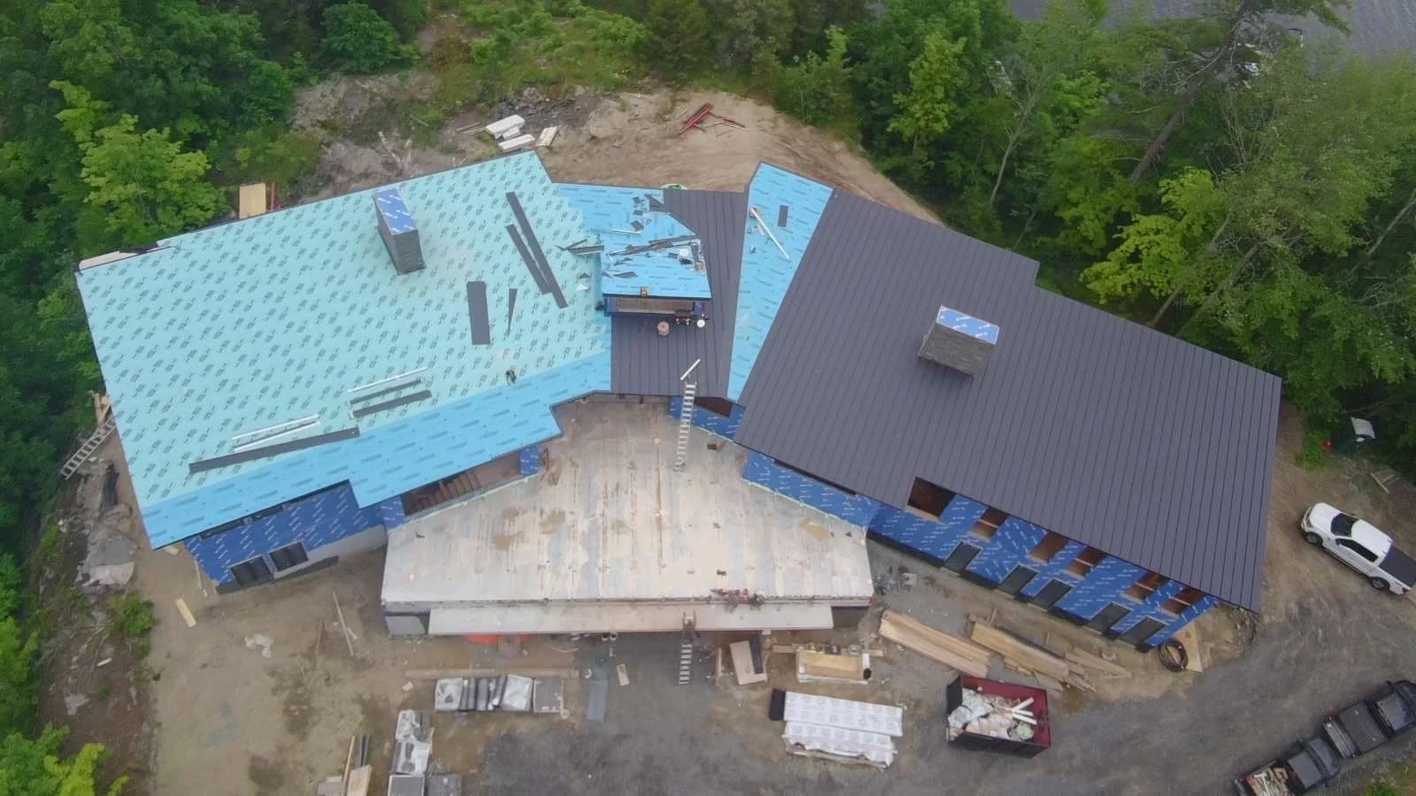 Roof installation in progress with membrane and metal panels visible