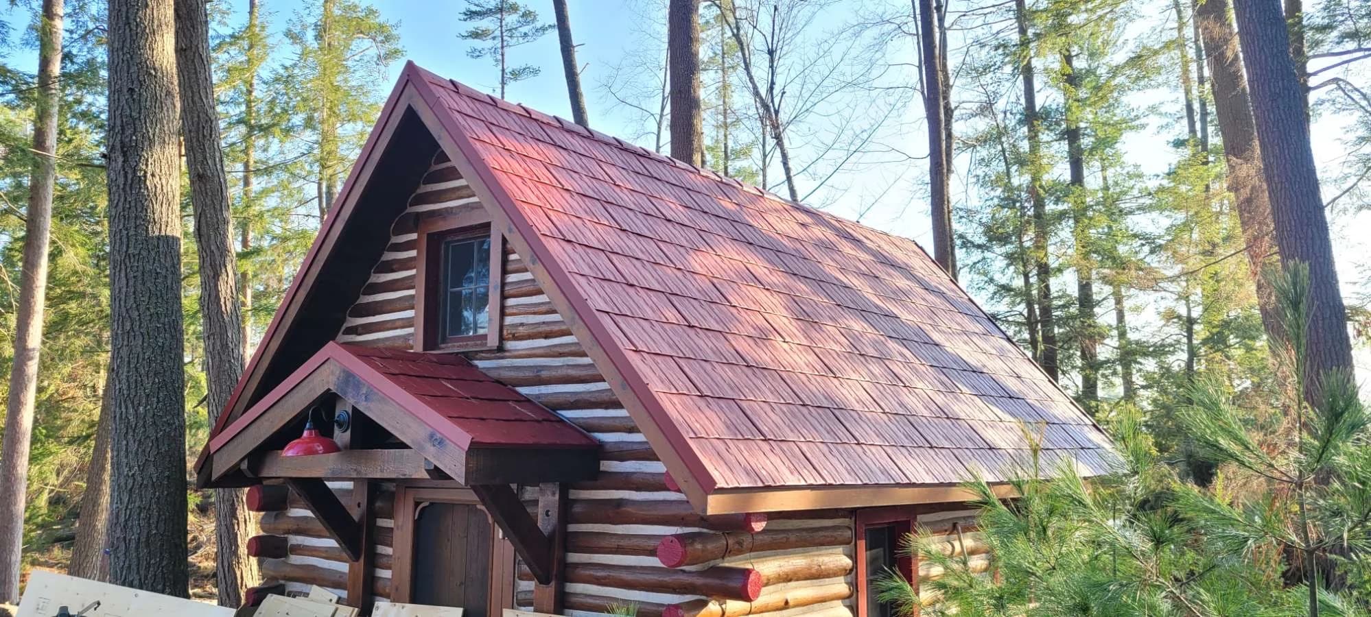 Red metal shingle roof on a small timber cabin