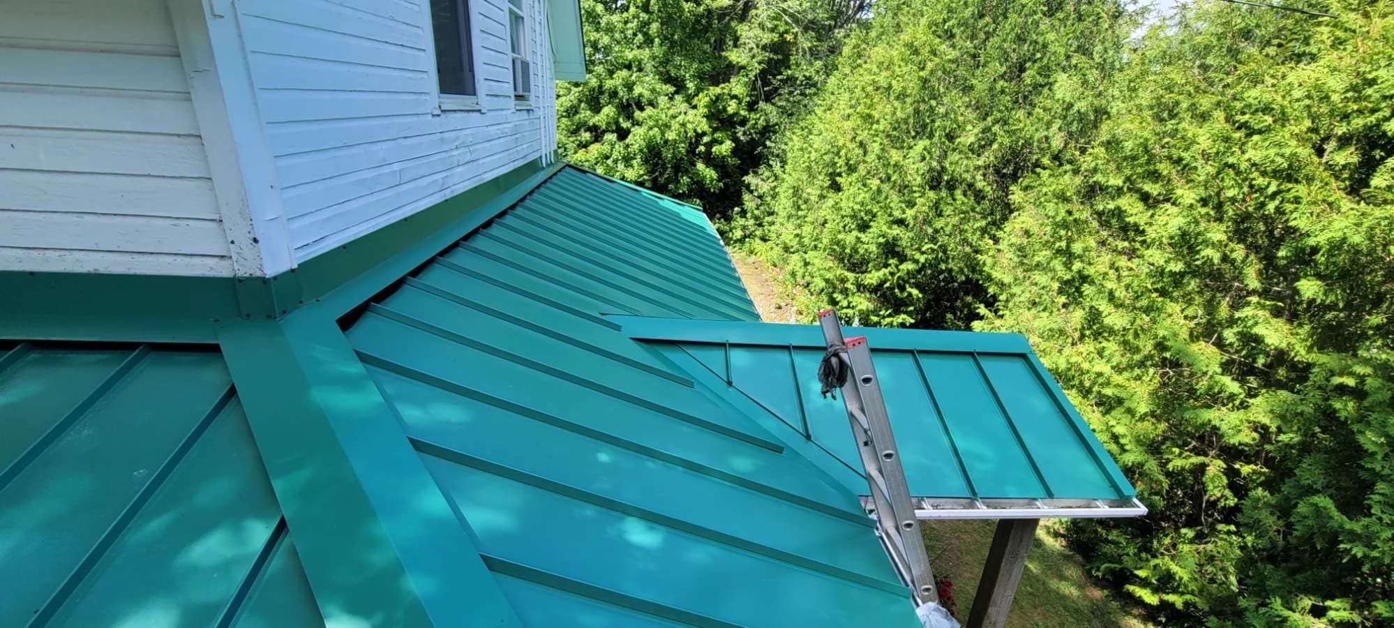 Green standing seam roof beside a house