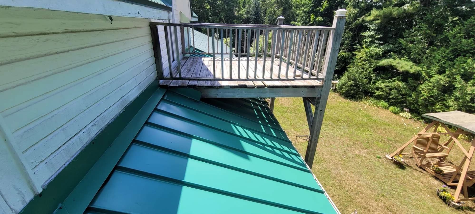 Green metal roof beneath an upper balcony