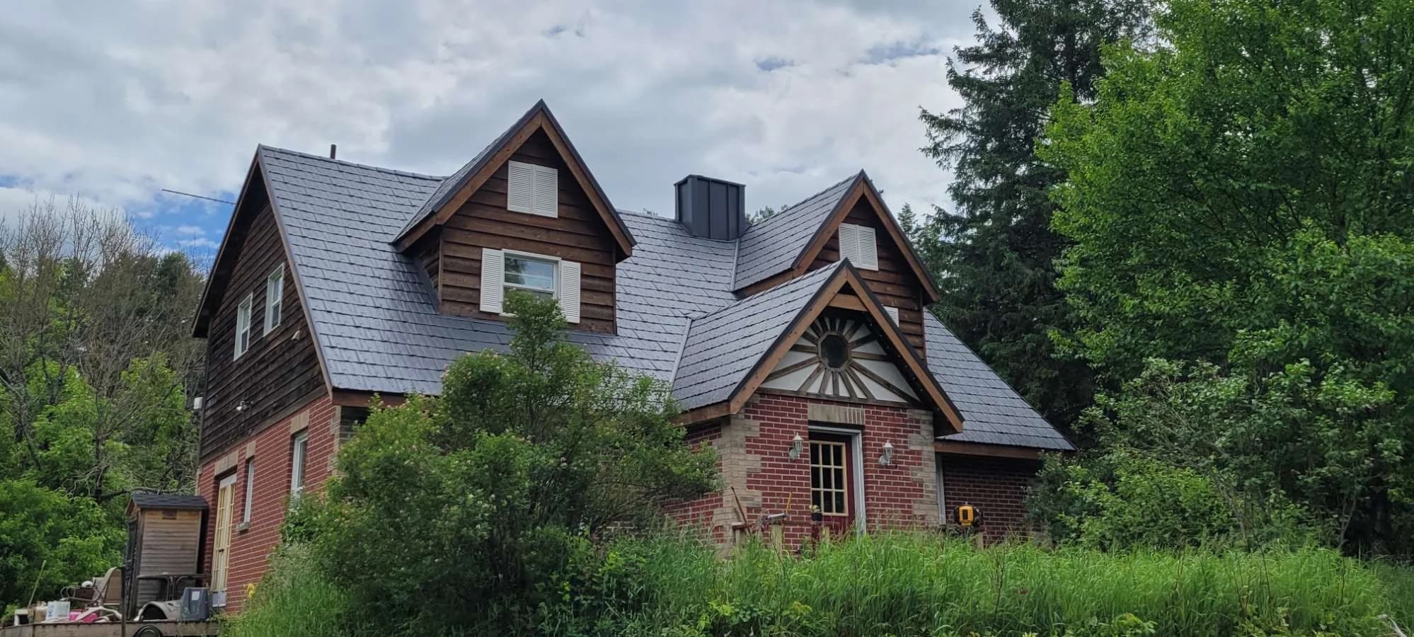 Metal shingle roof on a timber and brick home surrounded by trees