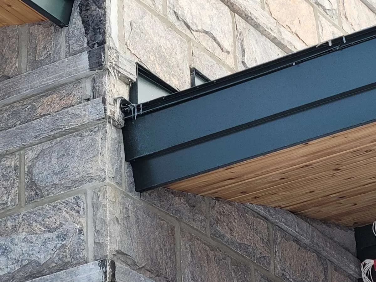 Metal roof edge and flashing meeting a stone wall