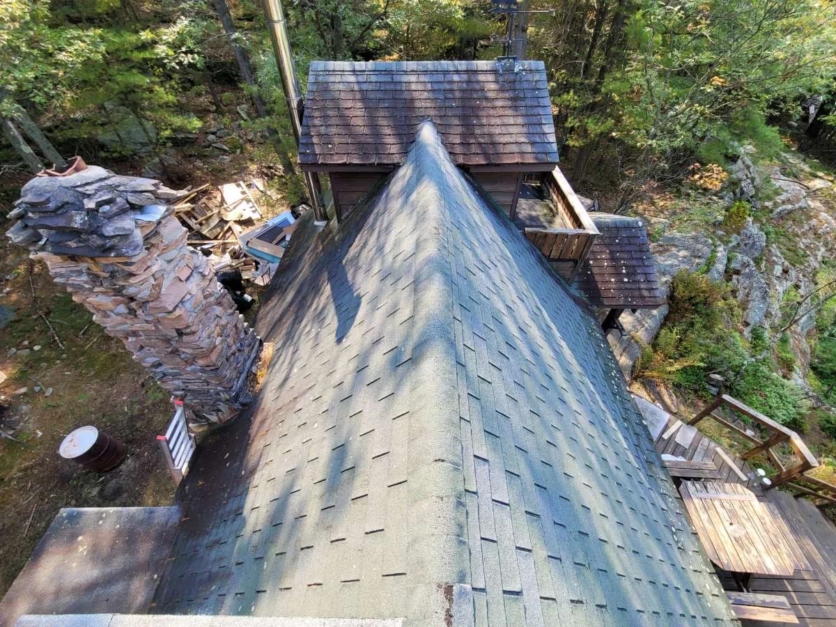 View along a metal shingle roof ridge in a wooded setting