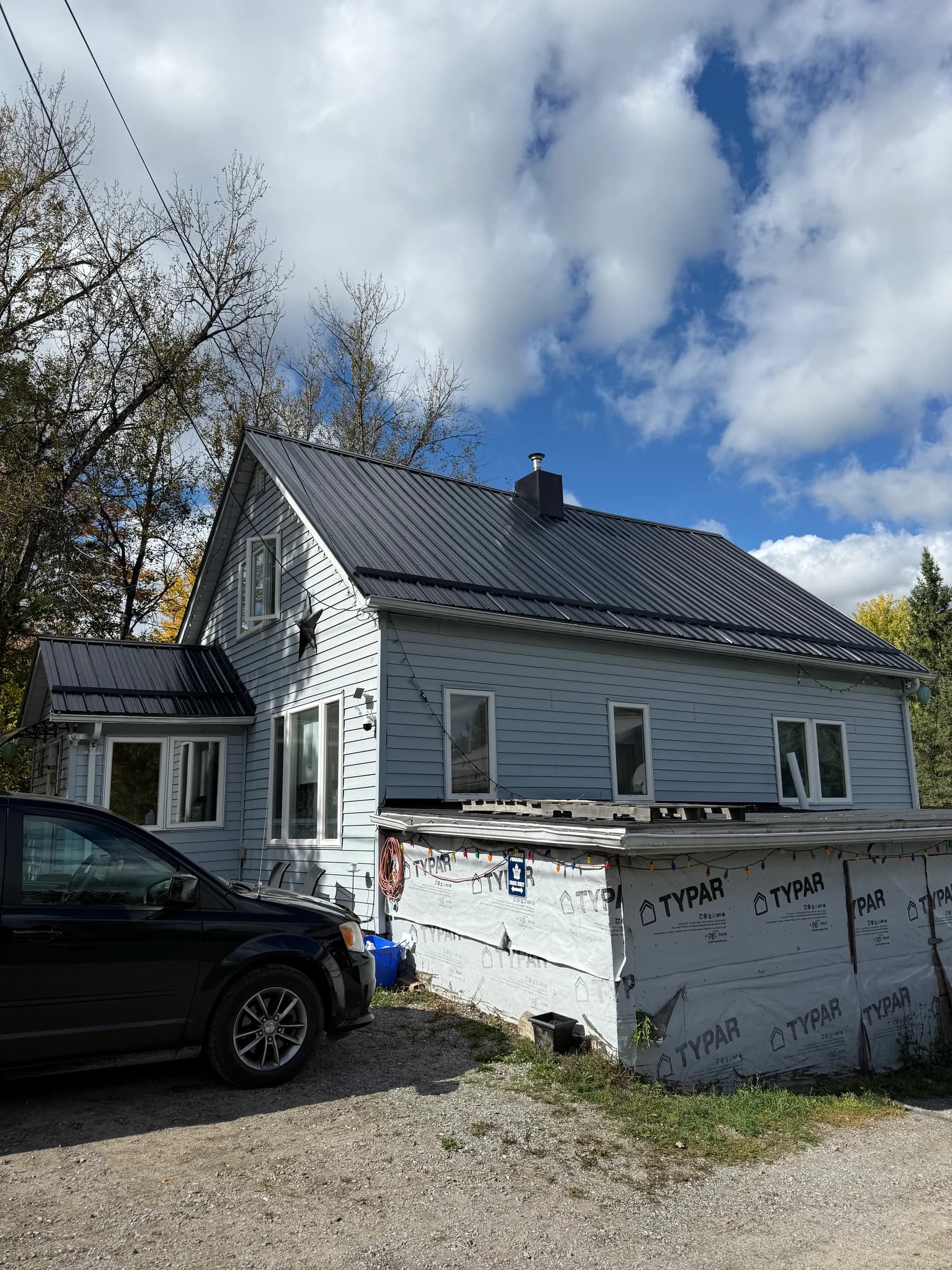 Dark ribbed metal roof on a light-coloured house during exterior work